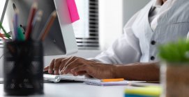 Вид збоку посередині чоловіка, що сидить за столом, використовуючи комп'ютер у сучасному офісі творчого бізнесу — стокове фото