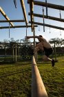 Vue latérale d'un jeune homme caucasien torse nu sautant par-dessus un obstacle dans une salle de gym extérieure lors d'une séance d'entraînement bootcamp — Photo de stock