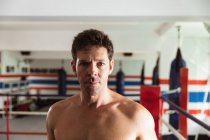 Retrato de cerca de un joven boxeador caucásico en un ring de boxeo mirando a la cámara - foto de stock