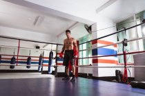 Retrato de um jovem boxeador caucasiano em pé em um ringue de boxe antes de uma luta — Fotografia de Stock
