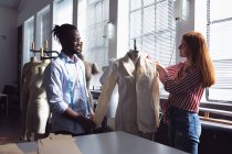Seitenansicht eines jungen afrikanisch-amerikanischen Mannes und einer jungen kaukasischen Modestudentin, die gemeinsam an einem Design in einem Studio der Modehochschule arbeiten — Stockfoto