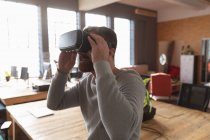 Side view close up of a young Caucasian man wearing a VR headset in a creative office — Stock Photo
