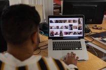 Nahaufnahme eines jungen Mannes mit gemischter Rasse, der an einem Schreibtisch sitzt und einen Laptop in einem Kreativbüro benutzt — Stockfoto
