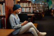 Side view close up of a young Asian female student wearing a turban using a smartphone in a library — Stock Photo
