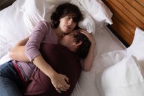 Vista frontal de cerca de un joven hombre y mujer caucásicos durmiendo y abrazándose en una cama - foto de stock