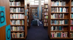 Vorderseite einer jungen asiatischen Studentin mit Turban, die ein Buch liest und in einer Bibliothek studiert — Stockfoto