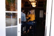Vista laterale di una giovane coppia caucasica felice che si rilassa insieme in vacanza in un bar — Foto stock