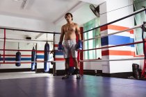 Передній вигляд молодої змішаної раси чоловічий боксер стоїть в боксерському кільці перед бійкою — стокове фото