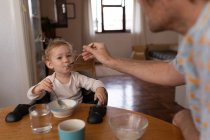 Front view close up of a young Caucasian father feeding his baby with a spoon — Stock Photo