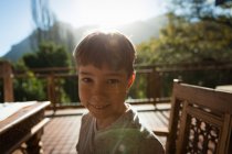 Ritratto ravvicinato di un ragazzo caucasico pre-adolescente seduto a un tavolo in un giardino, sorridente alla telecamera — Foto stock