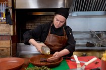 Nahaufnahme einer jungen kaukasischen Köchin, die in einer Restaurantküche Fleisch in einem Gericht zubereitet — Stockfoto