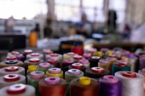 Bobbins of colored threads in the foreground in the workshop at a hat factory — Stock Photo
