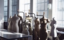 Vista frontal de un grupo de maniquíes de pie frente a una ventana en un estudio en una universidad de moda - foto de stock