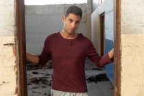 Портрет молодого чоловіка, що стояв у дверях, дивлячись на камеру в покинутому складі — стокове фото