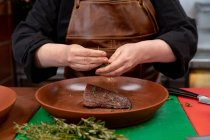 Vista frontale metà sezione di chef donna guarnire la carne in un piatto in una cucina ristorante — Foto stock