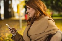 Woman using mobile phone in the park. — Stock Photo