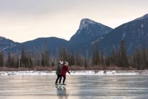 Вид збоку молоді кавказька пара на ковзанах разом в природному Сніжному пейзажі — стокове фото