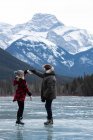 Vista lateral de la joven pareja caucásica bailando mientras está de pie en el paisaje nevado natural - foto de stock