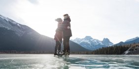 Vista lateral de pareja romántica joven caucásica de pie en el paisaje nevado natural en el fondo - foto de stock