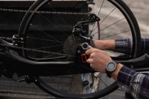 Close up of hands of man in a wheelchair assembling a recumbent bicycle — Stock Photo