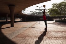 Вид збоку молоді кавказька жінка носити спортивний одяг розмахуючи Гирі вага над головою під час тренування в сонячний день в парку — стокове фото