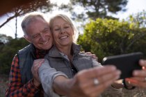 Vista frontal de cerca de un hombre y una mujer caucásicos maduros tomando una selfie en un entorno rural - foto de stock