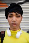 Портрет крупным планом модного молодого трансгендерного взрослого человека на улице в берете с граффити на заднем плане — стоковое фото