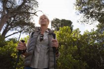 Front view close up of a mature Caucasian woman holding Nordic walking sticks and admiring the view, with countryside behind her — Stock Photo
