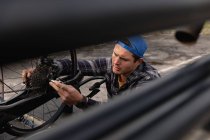 Side view close up of a young Caucasian man in a wheelchair assembling a recumbent bicycle in a car park — Stock Photo