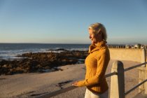 Side view of a mature Caucasian woman admiring the view by the sea at sunset — Stock Photo