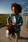 Вид спереди на смешанную расу: мальчик-подросток играет на детской площадке, стоя с лошадью-хобби в солнечный день — стоковое фото