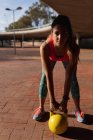 Вид спереду крупним планом молода кавказька жінка носіння спортивного одягу спираючись вперед проведення Гирі вага під час тренування в сонячний день в парку — стокове фото