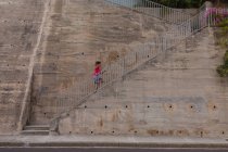 Vista laterale di una giovane donna caucasica che indossa vestiti sportivi correndo su per i gradini durante un allenamento in una giornata di sole — Foto stock