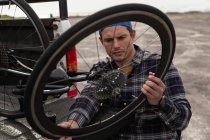 Nahaufnahme eines jungen kaukasischen Mannes im Rollstuhl, der ein Liegefahrrad aus dem Fond seines Autos holt, um es zusammenzubauen, mit einem Rad auf einem Parkplatz am Meer — Stockfoto