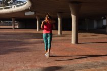 Rückansicht einer jungen kaukasischen Frau in Sportkleidung, die während eines Trainings an einem sonnigen Tag in einem Park läuft — Stockfoto
