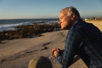 Vista lateral de perto de um homem caucasiano maduro admirando a vista pelo mar ao pôr do sol — Fotografia de Stock