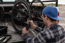 Rear view close up of a young Caucasian man in a wheelchair taking a recumbent bicycle out of the back of his car to assemble it — Stock Photo