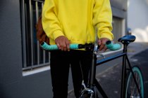 Vue de face de la section médiane d'un homme à la mode dans la rue, tenant un vélo — Photo de stock