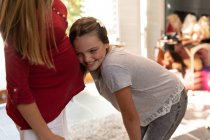 Vista lateral de uma menina caucasiana tween inclinado e ouvir a barriga de sua mãe grávida em sua sala de estar — Fotografia de Stock