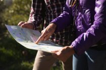 Вид сбоку на среднюю часть мужчины и женщины, читающие карту во время прогулки в сельской местности — стоковое фото