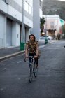 Vue de face d'un jeune homme caucasien faisant du vélo dans une rue urbaine, rentrant du travail le soir — Photo de stock