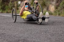 Front view of a young Caucasian man in sportswear on a recumbent bicycle cycling on a country road — Stock Photo