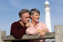 Nahaufnahme eines erwachsenen kaukasischen Paares, das an einem sonnigen Tag die freie Zeit auf einer Bank in der Nähe eines Leuchtturms genießt — Stockfoto