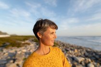 Вигляд збоку біля кавказької жінки, яка у сонячний день насолоджується вільним часом на пляжі біля моря. — стокове фото