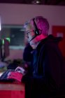 Seitenansicht eines kaukasischen Spielers, der in einem kreativen Büro arbeitet, Lesebrille und Headset trägt und auf den Computerbildschirm blickt — Stockfoto