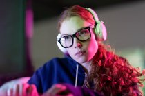 Front view of a young Caucasian woman working in a creative office, wearing glasses, listening to music with headphones on — Stock Photo