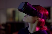 Vista lateral de una joven mujer caucásica que trabaja en una oficina creativa, con auriculares VR. Este es un negocio de puesta en marcha - foto de stock