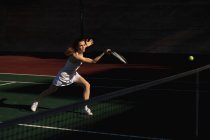 Вид сбоку на молодую кавказку и мужчину, играющего в теннис в солнечный день, женщину, бегущую на бал — стоковое фото