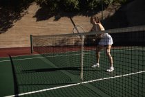 Vista lateral de uma jovem caucasiana jogando tênis em um dia ensolarado, segurando uma raquete e esperando a bola — Fotografia de Stock