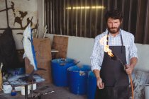 Artesano atento sosteniendo quemador en taller - foto de stock
